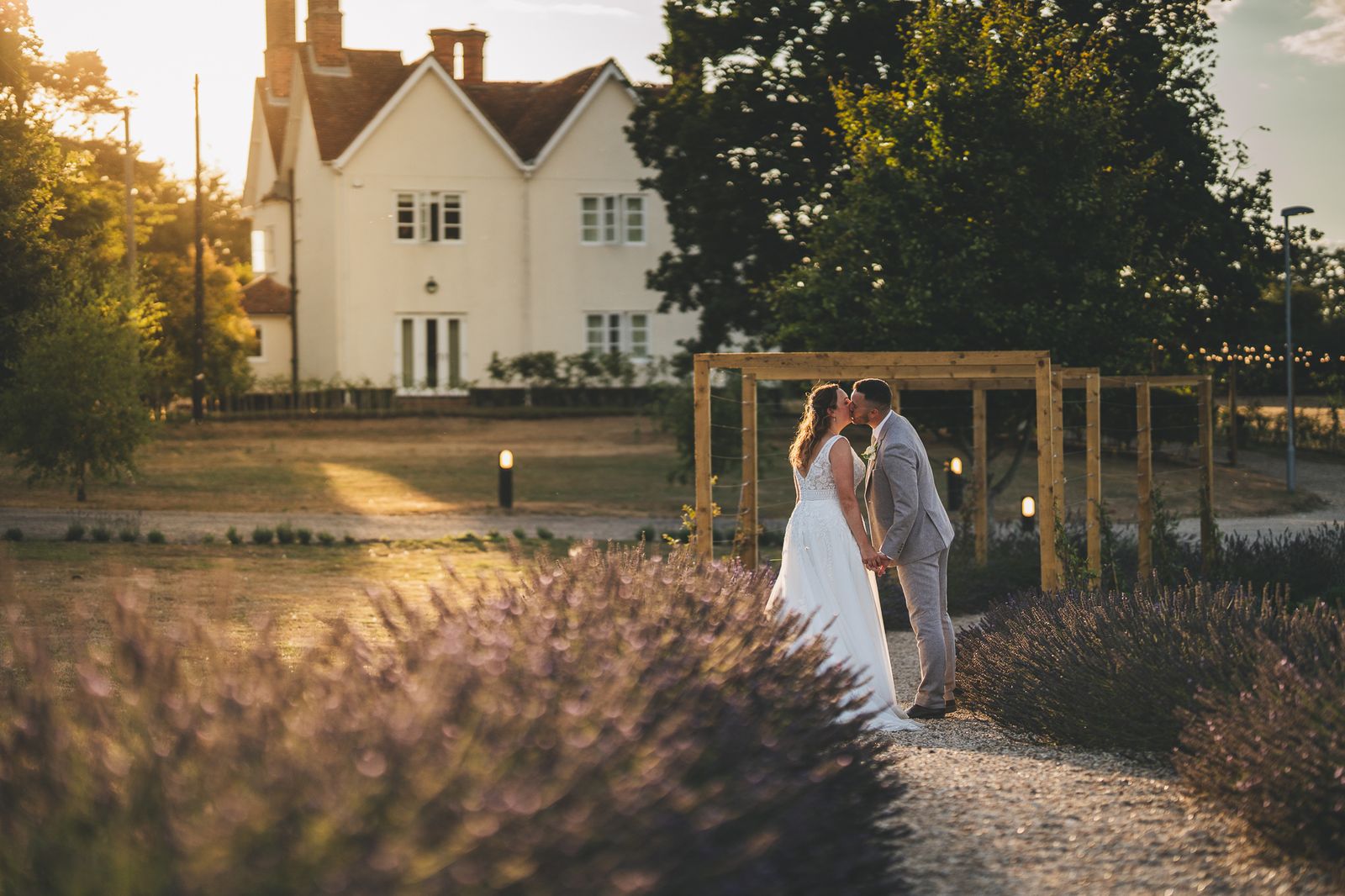 Couple sharing a kiss under a wooden pergola in golden light